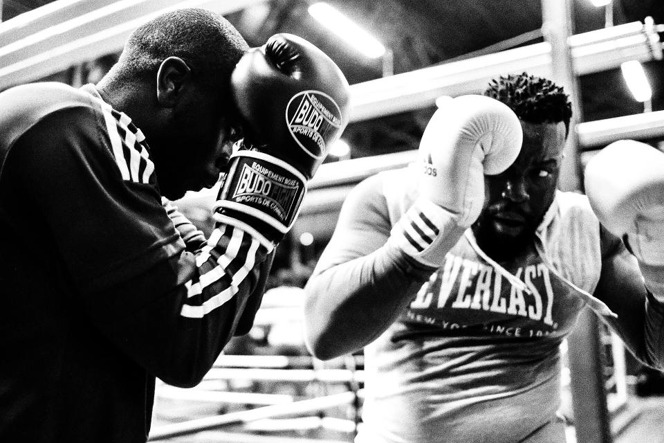 Due pugili si allenano in una palestra di boxe, in bianco e nero.